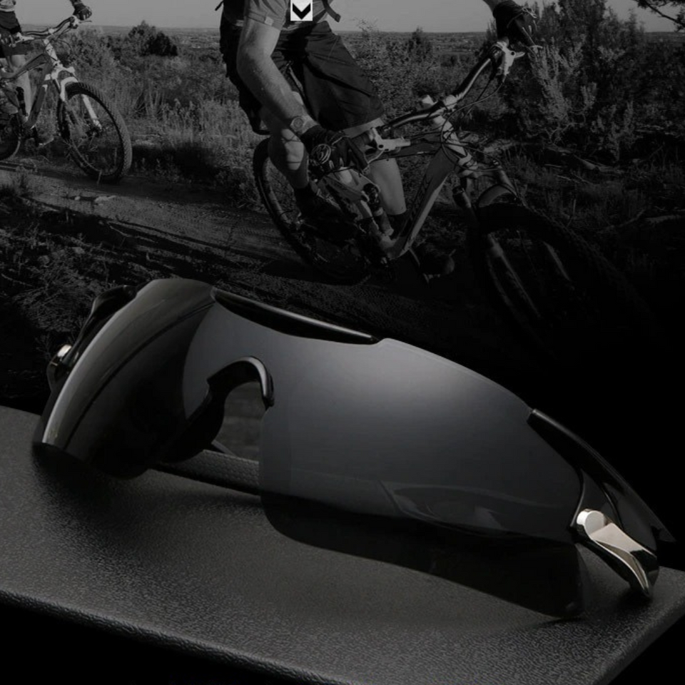 Óculos de sol Sport modelo esportivo em ângulo imclinado na cor preto, com ciclistas no fundo da foto em preto e branco, disponível em: ethosloja.com.br
